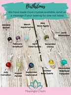 Collection of birthstone charms with labels on a wooden surface, branded 'Meaningful Charm'.