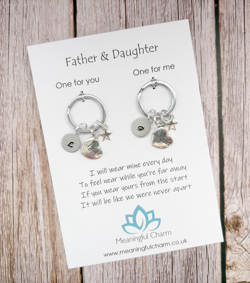 Two keychains on a card with a message for a father and daughter, on a wooden surface.