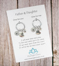 Two keychains on a card with a message for a father and daughter, on a wooden surface.