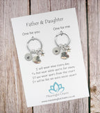 Two keychains on a card with a message for a father and daughter, on a wooden surface.