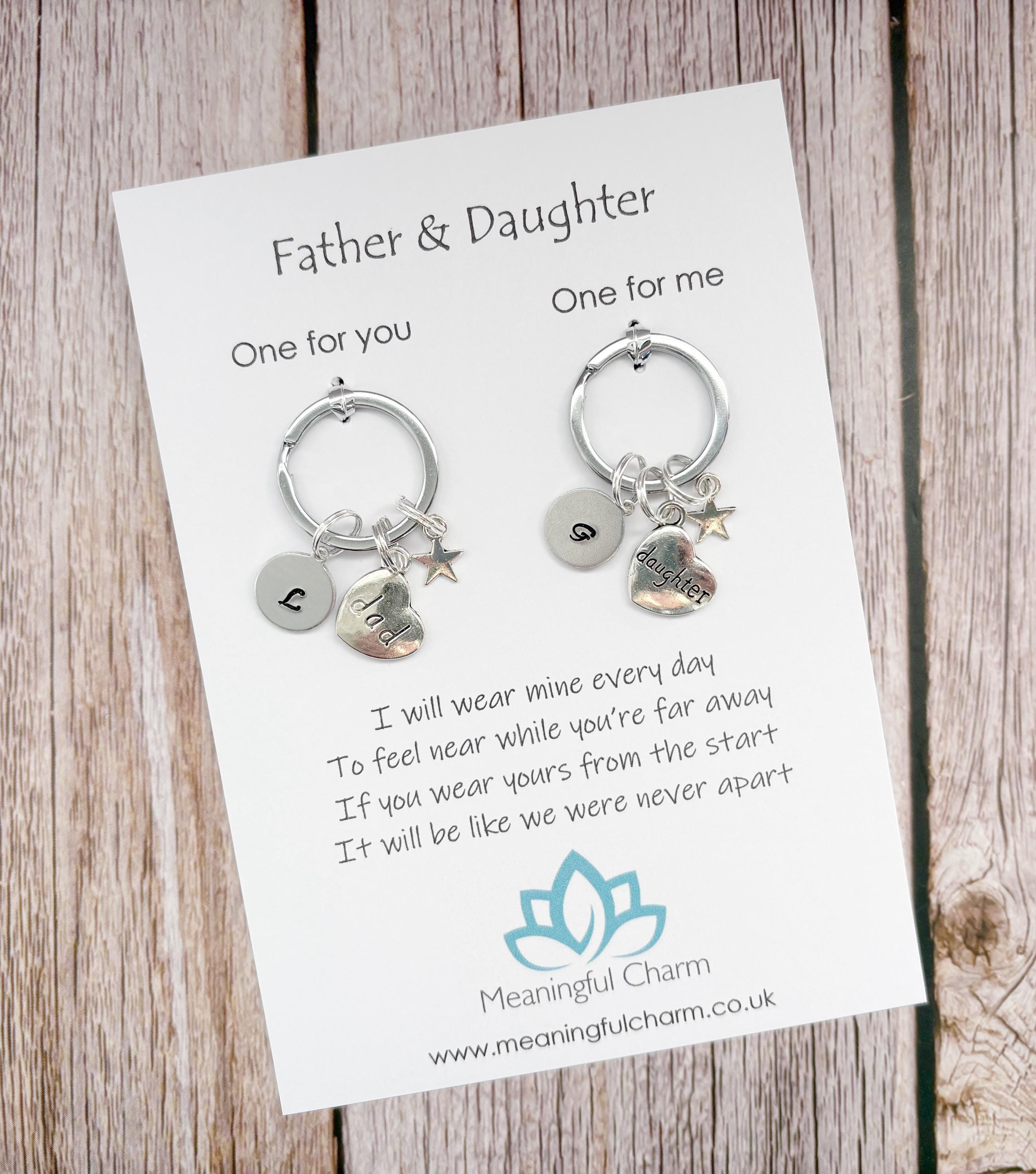Two keychains on a card with a message for a father and daughter, on a wooden surface.