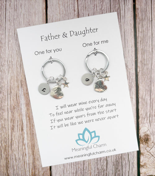 Two keychains on a card with a message for a father and daughter, on a wooden surface.