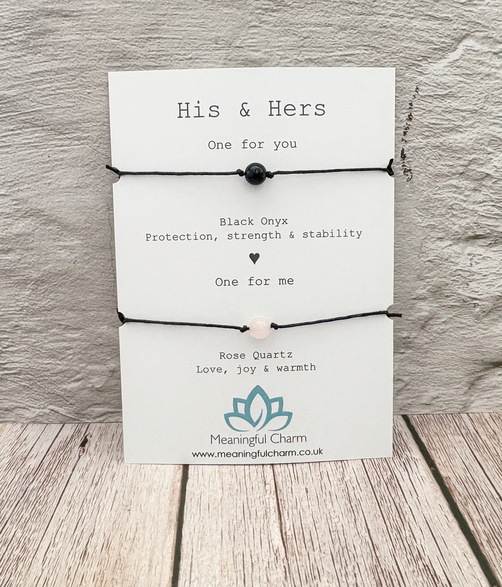 Pair of black bracelets with text on a white card against a wooden background