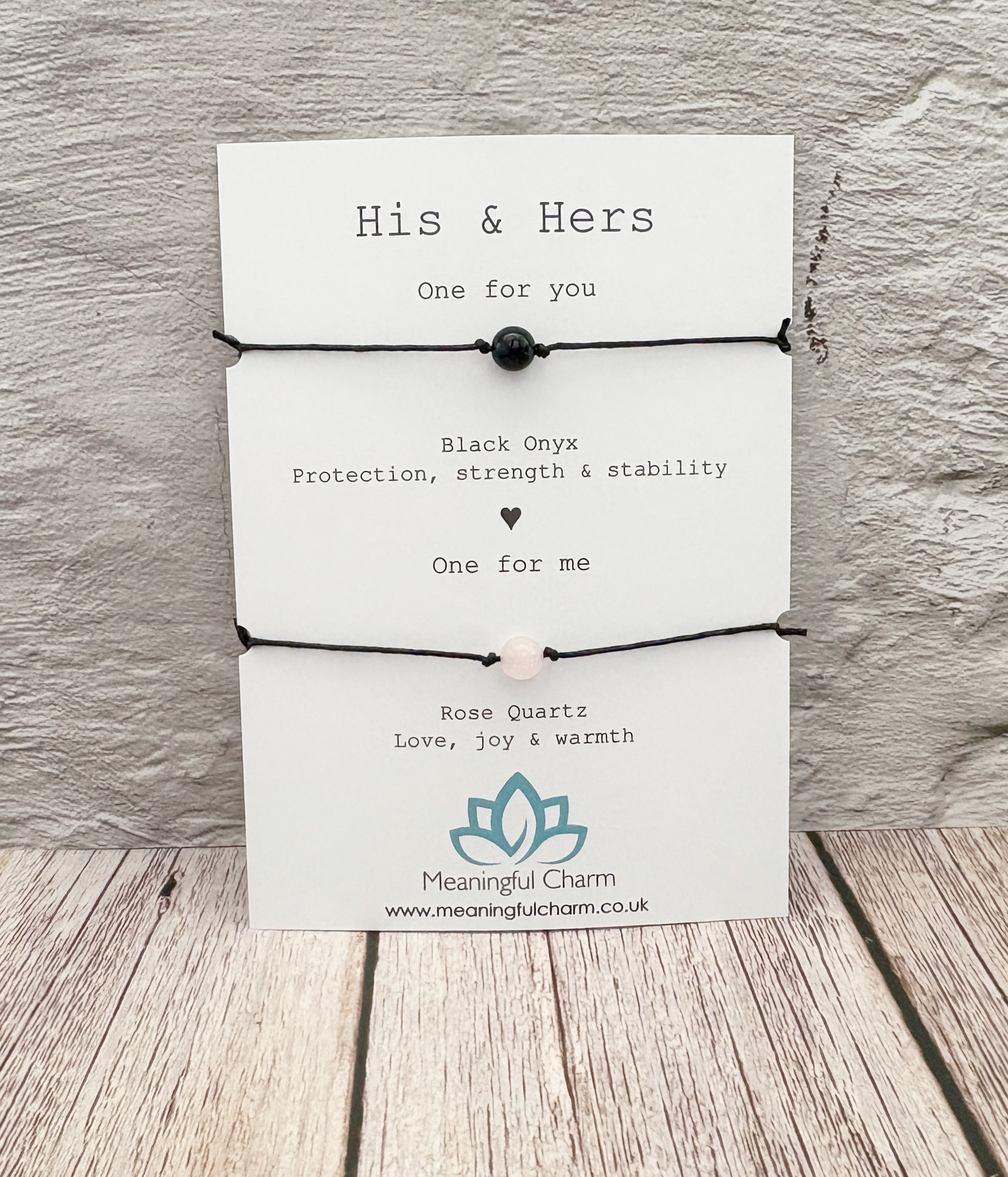 Pair of black bracelets with text on a white card against a wooden background