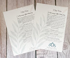 Two printed cards with inspirational poetry titled 'I See You' laid on a rustic wood surface. The cards are off-white with gray botanical leaf illustrations and black text, and the brand name Meaningful Charm is visible at the bottom.