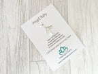 Angel Baby charm on a card with text and branding on a wooden surface