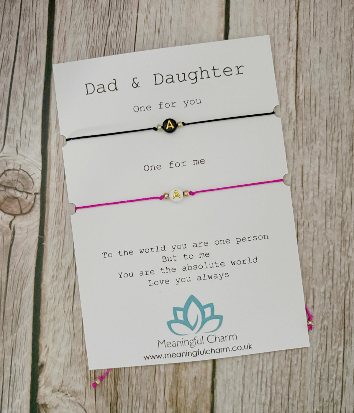 Two bracelets with cards for 'Dad & Daughter' on a wooden surface.