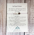A square white card with printed text and a teal lotus logo, placed on a rustic whitewashed wooden surface. The card appears to be the product itself rather than an auxiliary chart, so this is Product/Packaging.