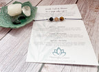 A printed card set from Meaningful Charm titled 'Walk Tall & Shine' laid on a whitewashed wood surface, alongside a green ceramic dish holding crystals and a small beaded bracelet.